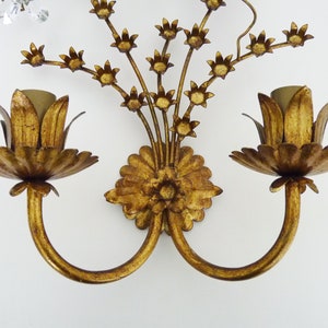 May include: Gold metal wall sconce with two flower-shaped light fixtures and a floral design.