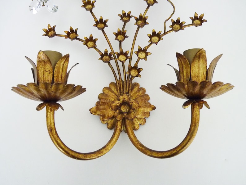 May include: Gold metal wall sconce with two flower-shaped light fixtures and a floral design.