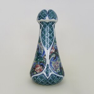 May include: A blue and white ceramic bottle stopper with a floral design. The stopper has a bulbous top and a narrow neck.