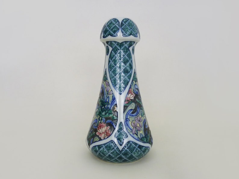 May include: A blue and white ceramic bottle stopper with a floral design. The stopper has a bulbous top and a narrow neck.