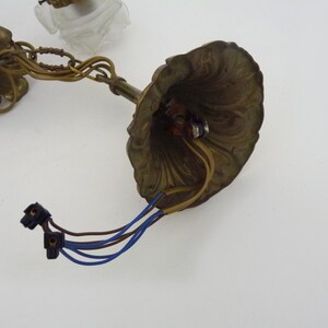 Puede incluir: Luminaria de ara&ntilde;a de lat&oacute;n antiguo con detalles florales y de hojas. La luminaria tiene una capota decorativa, cableado y una cadena para colgar. Los cables son azules y marrones. Dise&ntilde;ado para una l&aacute;mpara de techo.