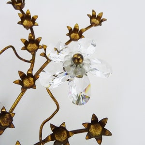 May include: A gold metal tree with crystal flowers. The tree has a delicate, intricate design with many branches and leaves. The flowers are made of clear crystal and have a sparkling, iridescent finish.
