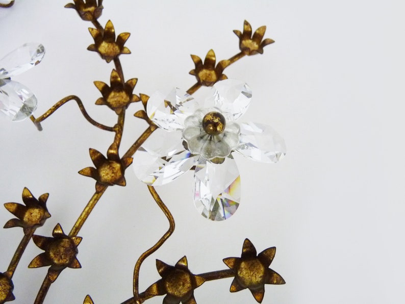 May include: A gold metal tree with crystal flowers. The tree has a delicate, intricate design with many branches and leaves. The flowers are made of clear crystal and have a sparkling, iridescent finish.