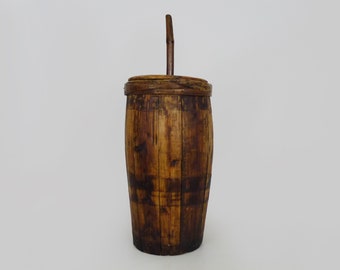May include: A wooden barrel with a handle and a lid. The barrel is made of natural wood and has a rustic appearance.