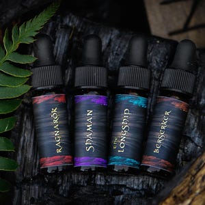 May include: Four small glass bottles with dropper tops, each with a different colored label and text. The labels read "Ragnarok", "SidaMan", "The LongShip", and "Berserker".