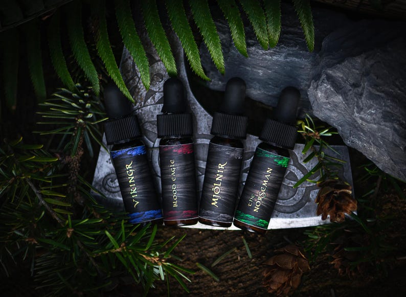 May include: Four small black bottles with gold lettering and different colored liquids. The bottles are labeled "Viking", "Blood Eagle", "Mjolnir", and "The Norsemen".