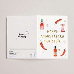 May include: A folded greeting card with a white background. The right side features illustrations of chili peppers, hot sauce bottles, and the text "HAPPY ANNIVERSARY HOT STUFF." The left side has the text "lauren Barclay."