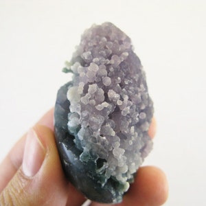 May include: A purple and green agate geode with a cluster of small crystals. The geode is about 2 inches tall and 1.5 inches wide.