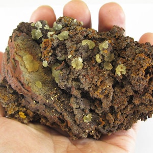 May include: A large, rough, brown rock with clusters of small, light yellow crystals. The rock has a textured surface and appears to be a mineral specimen.
