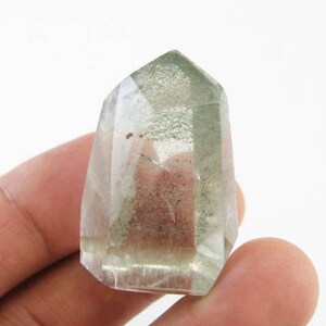 Puede incluir: Una punta de cristal verde claro con una doble terminación. El cristal tiene un aspecto nublado y lechoso con inclusiones.