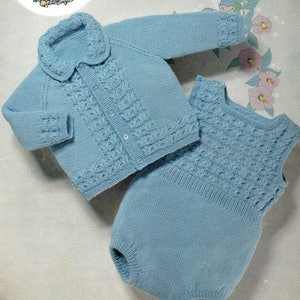 May include: A knitted baby outfit in a light blue colour. The outfit includes a cardigan with a collar and a matching onesie. Both pieces feature a delicate cable knit pattern.
