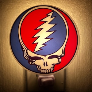 May include: A night light featuring a red, white, and blue Grateful Dead Steal Your Face logo. The logo is a skull with a lightning bolt in the middle.