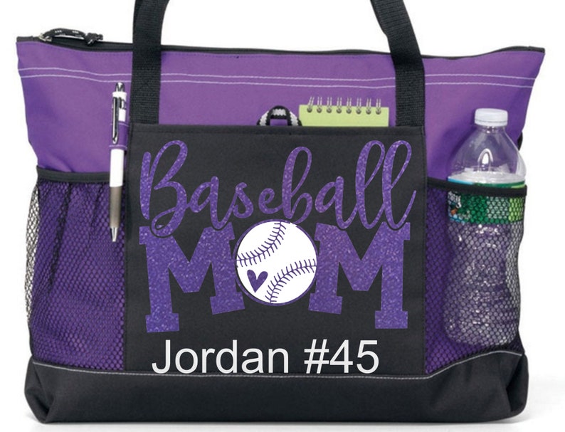 May include: Purple and black tote bag with a zipper closure and mesh side pockets. The bag has a design that says "Baseball Mom" with a baseball and a heart. The name "Jordan #45" is printed below the design.