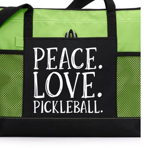 May include: Black and green tote bag with a mesh pocket. The bag has a white graphic that says "Peace. Love. Pickleball."