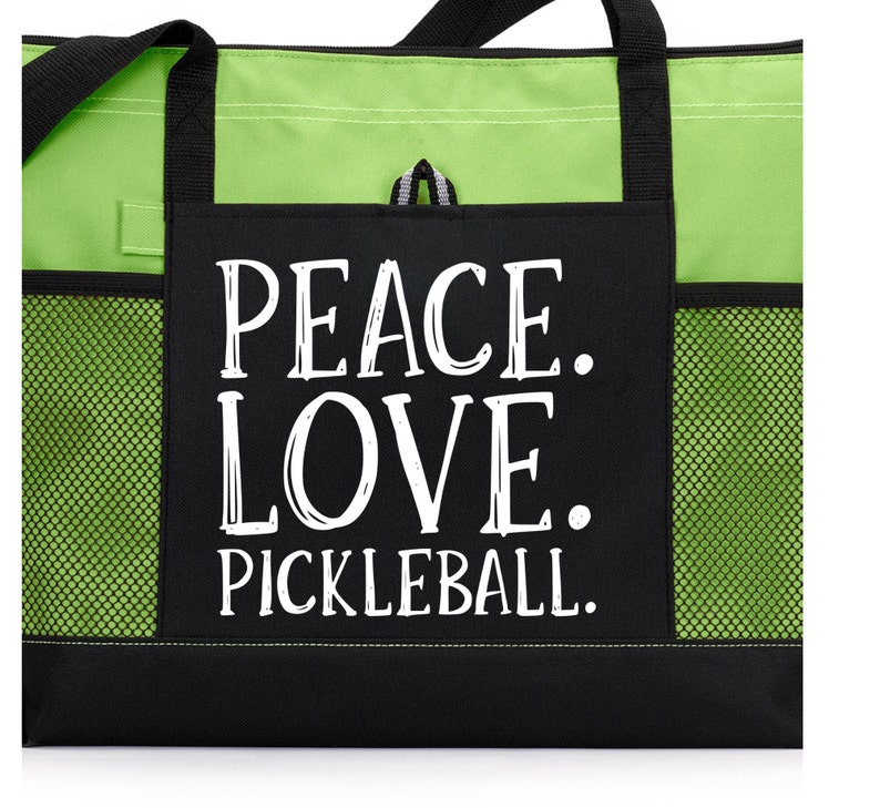 May include: Black and green tote bag with a mesh pocket. The bag has a white graphic that says "Peace. Love. Pickleball."