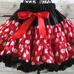 Può includere: Gonna tutu a pois rossi e bianchi con una cintura in raso nero e un fiocco in raso rosso. La gonna ha più strati di tulle e un bordo in pizzo nero.