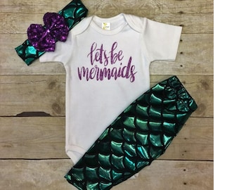 Peut inclure: Un body blanc avec le texte "Let's be mermaids" en paillettes violettes. Le body est associé à un legging queue de sirène verte et un bandeau à paillettes violettes.