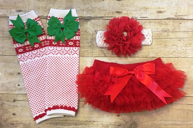 May include: Red and white knit leg warmers with green bows, a red tulle tutu with a red satin bow, and a red flower headband with a white crocheted band.