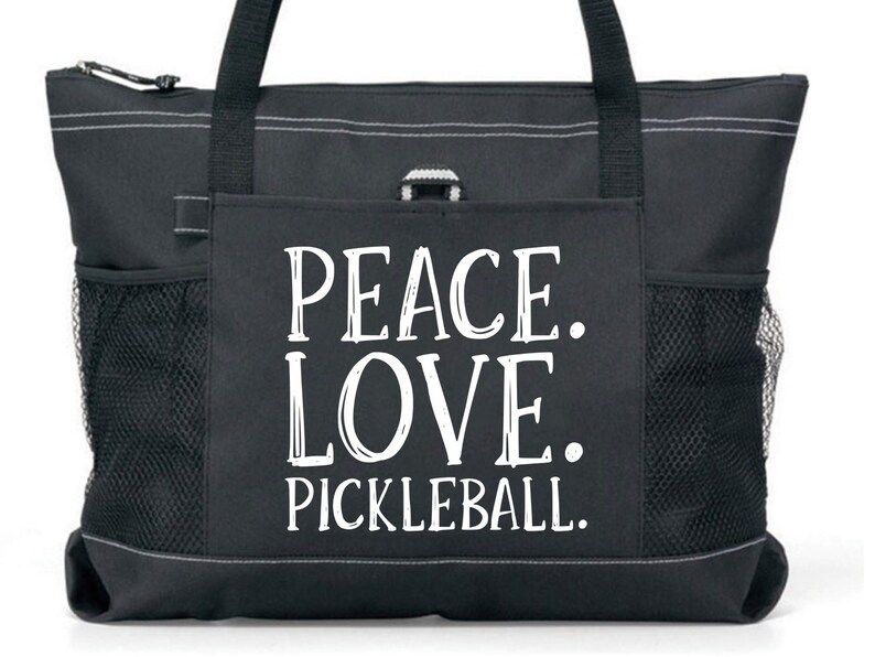 May include: Black tote bag with a large white pocket featuring the text "Peace. Love. Pickleball."