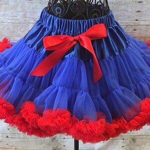 Peut inclure: Une jupe en tulle bleu avec un n&oelig;ud en satin rouge et une bordure &agrave; volants rouges.