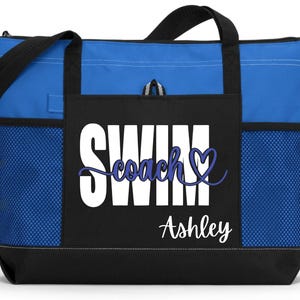 May include: Blue and black tote bag with the words "SWIM Coach Ashley" in white and blue script. The bag has black handles and a black base. Mesh pockets are on the sides.