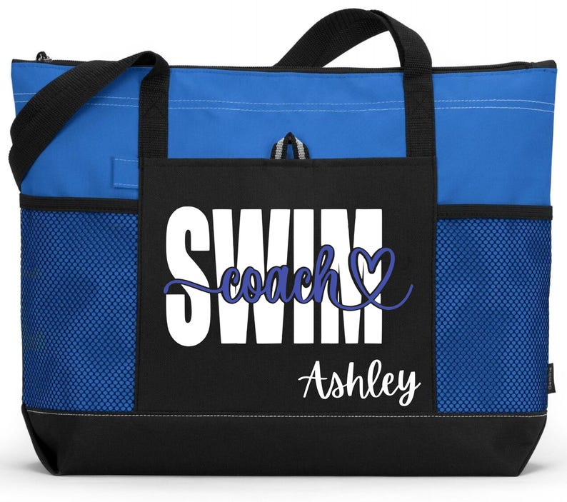May include: Blue and black tote bag with the words "SWIM Coach Ashley" in white and blue script. The bag has black handles and a black base. Mesh pockets are on the sides.