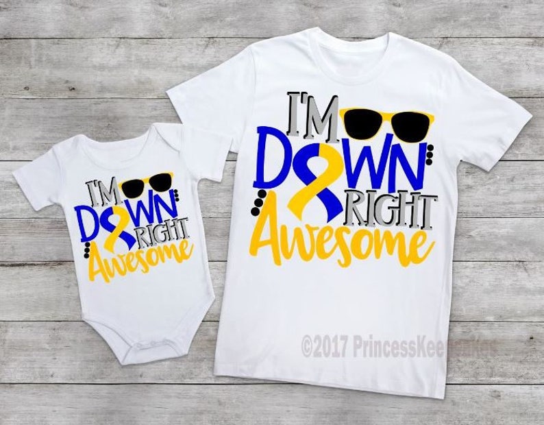 May include: Two white t-shirts with a blue and yellow ribbon design. The larger shirt says "I'm Down Right Awesome" with sunglasses. The smaller shirt says "I'm Down Right Awesome" with sunglasses.