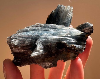 May include: A cluster of gray and black mica crystals with a shimmering, iridescent sheen. The crystals are arranged in a jagged, irregular shape, resembling a small mountain range.
