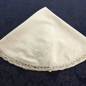 May include: White round tablecloth with a delicate lace trim and embroidered butterfly design.