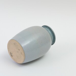 Pu&ograve; includere: Un vaso in ceramica blu chiaro con una glassa macchiettata. Il vaso ha un corpo arrotondato e un labbro leggermente svasato. Il fondo del vaso &egrave; contrassegnato da una piccola stella.