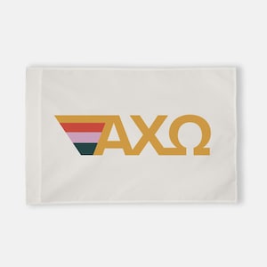 May include: White flag with a gold Greek letter design. The letters are "AXO" and are in a bold, sans-serif font. A colorful stripe design is behind the letters.