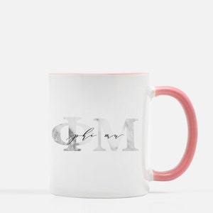 May include: White ceramic mug with a pink rim and handle. The mug features a marble-textured design with the letters "ΦΜ" and the text "phi mu" in black script.