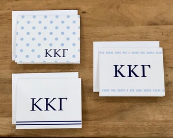 May include: Three white note cards with blue and navy blue designs. The cards feature the letters "KKG" in navy blue on each card. The first card has a light blue polka dot pattern, the second card has a light blue chevron pattern, and the third card has two navy blue stripes.