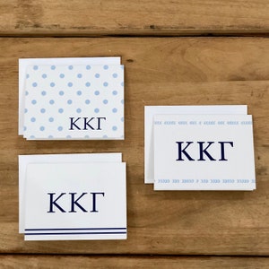 May include: Three white note cards with blue and navy blue designs. The cards feature the letters "KKG" in navy blue on each card. The first card has a light blue polka dot pattern, the second card has a light blue chevron pattern, and the third card has two navy blue stripes.