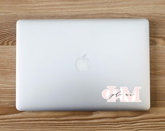 May include: A white laptop computer with a pink and white sticker that says "Phi Mu" in cursive script.