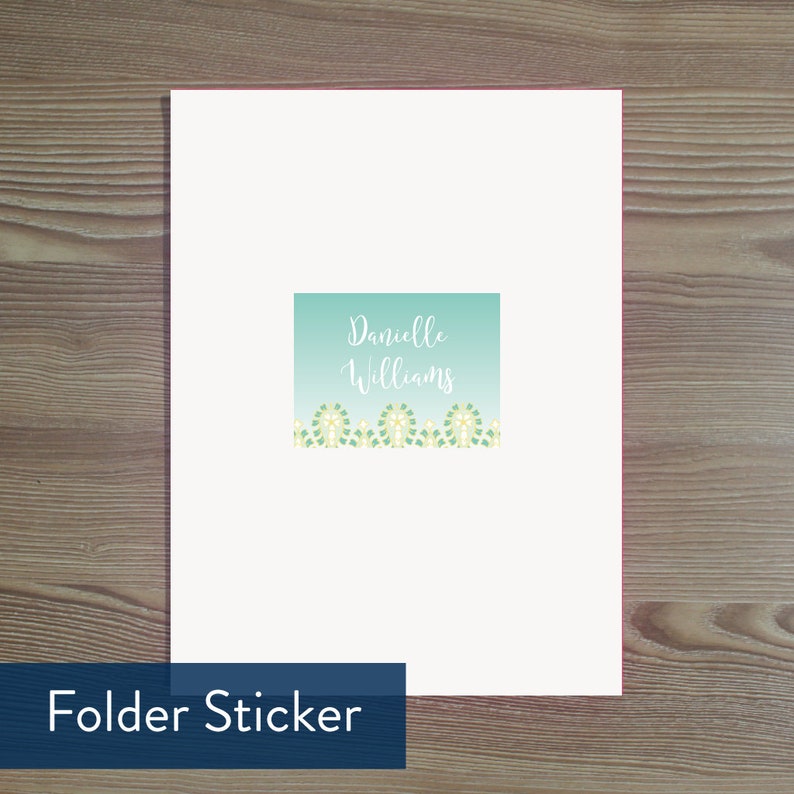 May include: A white folder sticker with a light blue background and a white border. The sticker has the text "Danielle Williams" in white cursive font. The bottom of the sticker has a row of green and yellow flowers.