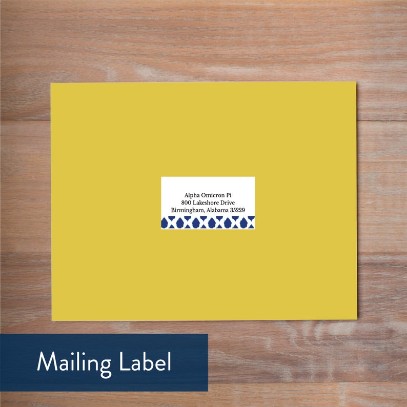 May include: A yellow mailing label with a blue and white patterned border. The label has the text "Alpha Omicron Pi, 800 Lakeshore Drive, Birmingham, Alabama 35229" printed on it.