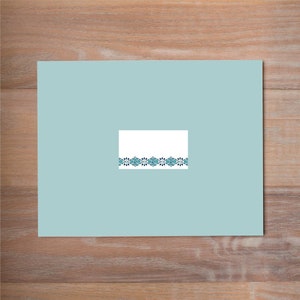 May include: A light blue card with a white rectangle in the center. The rectangle has a decorative border of teal blue and black floral designs.