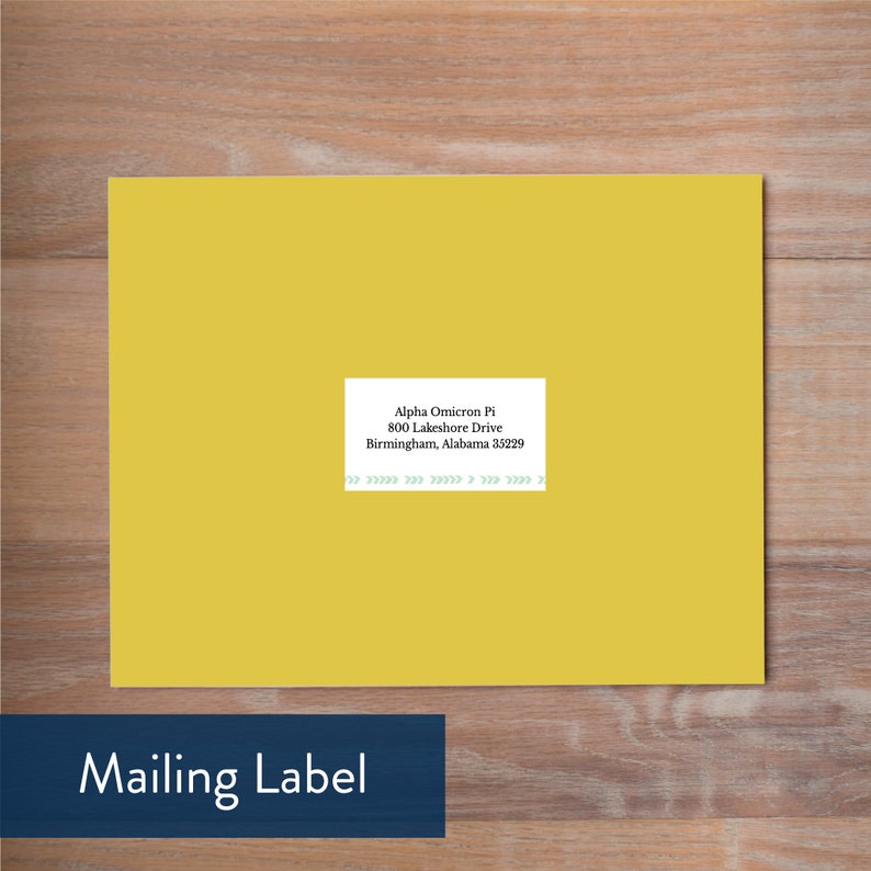 May include: A yellow mailing label with the text "Alpha Omicron Pi, 800 Lakeshore Drive, Birmingham, Alabama 35229". The label is on a wooden surface. The words "Mailing Label" are in a blue rectangle.