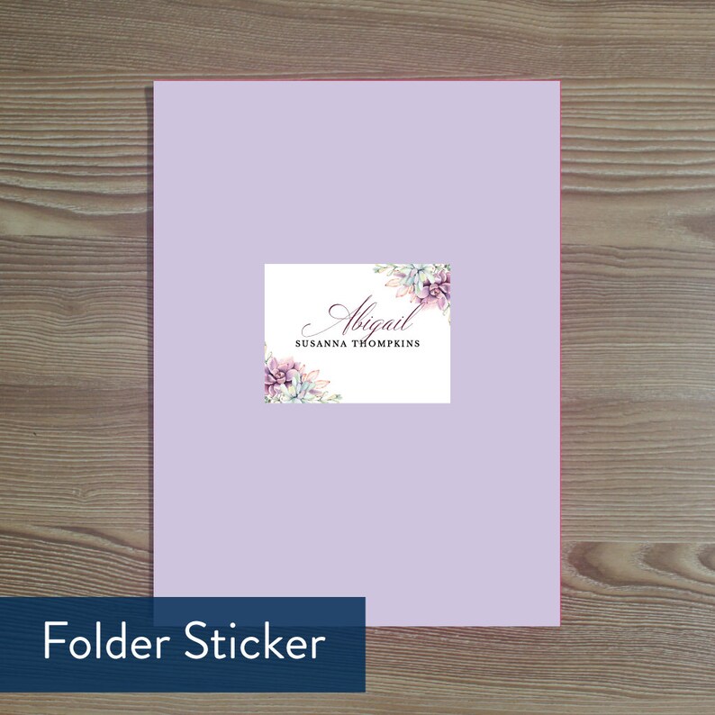 May include: A white folder sticker with a floral design in shades of purple and green. The sticker has the text "Abigail Susanna Thompkins" in a cursive font.