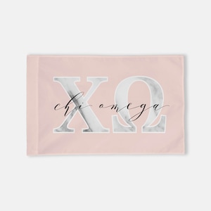 May include: A pink flag with a white marble design featuring the letters "XO" and the text "chi omega" in black cursive.