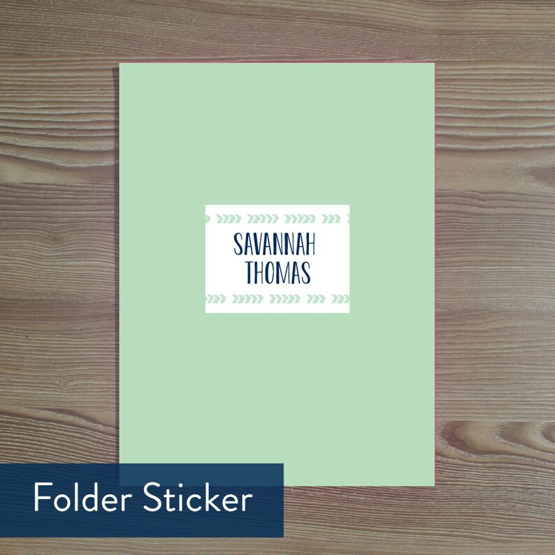 May include: A pale green folder with a white label bearing the name "Savannah Thomas" in navy blue. The label is decorated with light green arrow patterns. The words "Folder Sticker" are in a navy blue box at the bottom.