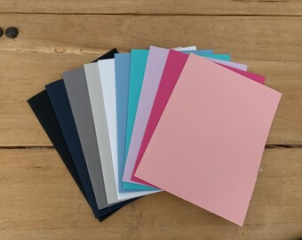 May include: A fan of 10 different colored sheets of paper. The colors are black, navy blue, gray, white, light blue, teal, lavender, pink, and light pink.