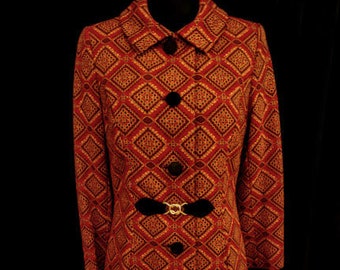 Puede incluir: Un abrigo largo de color rojo y dorado con estampado, con cinturón negro y botones negros.