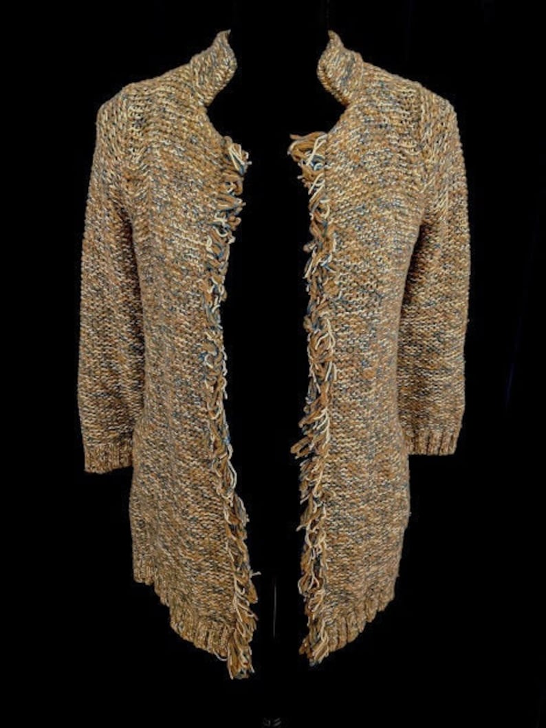May include: A long-sleeved cardigan with a brown, beige, and blue color scheme. The cardigan has a fringed trim along the edges and a slightly open front.
