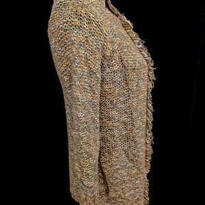 May include: A brown and blue knitted cardigan with a fringed hem. The cardigan is made of a soft, textured yarn.