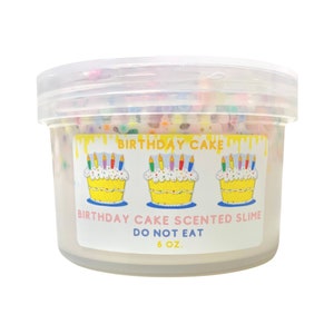 May include: A clear plastic container filled with white slime with colorful sprinkles. The container has a label that says "Birthday Cake Scented Slime" and "Do Not Eat" with a birthday cake graphic.