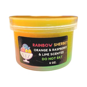 May include: A clear plastic container filled with a multi-colored slime. The container has a black label that reads "Rainbow Sherbet Orange & Raspberry & Lime Scented Do Not Eat 6 oz."
