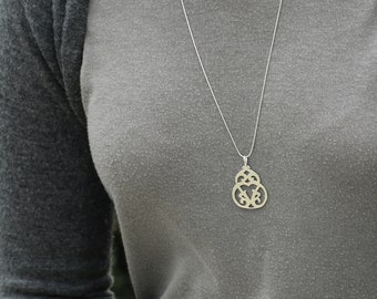 May include: A silver chain necklace with a delicate, ornate pendant. The pendant is a cutout design with a heart shape in the center.