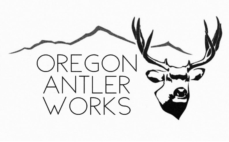 May include: Black and white logo for Oregon Antler Works. The design features a stylized deer head with large antlers, mountains, and the company name in a clean, sans-serif font.